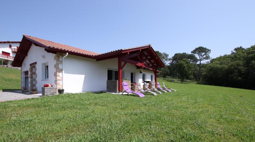 une petite maison blanche avec des chaises dans l'herbe dans l'établissement Saardia, à Ahetze