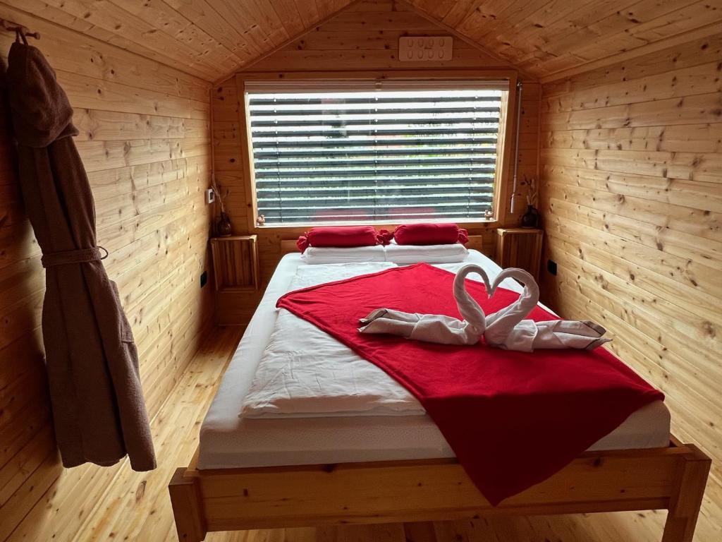 - une chambre avec un lit et une couverture rouge dans l'établissement Glamping NA BREJGI, à Filovci