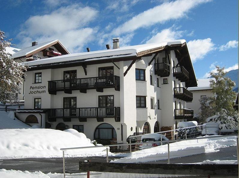 a large white building with snow on the ground at Jochum Hotel Garni in Fiss