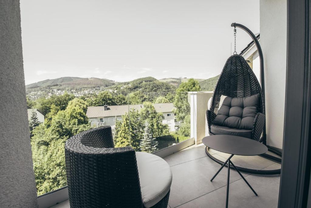uma varanda com uma cadeira de baloiço e uma mesa em Lenneapartments Premium em Plettenberg