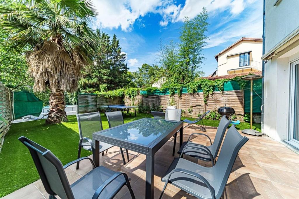 eine Terrasse mit einem Tisch, Stühlen und einem Grill in der Unterkunft Maison Frappaz 4 chambres avec jardin Villeurbanne in Villeurbanne