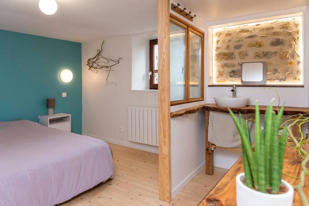 1 dormitorio con cama, lavabo y espejo en Maisonnette duplex avec jacuzzi/sauna attenant en Saint-Martin-des-Entrées