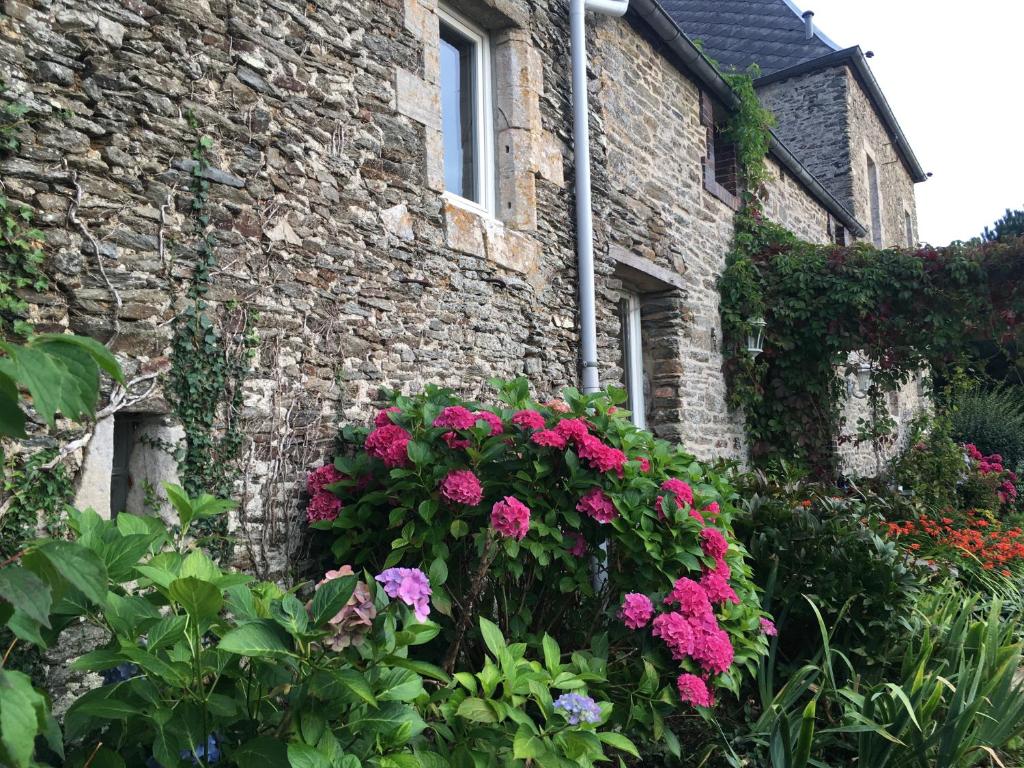 a stone house with flowers in front of it at La Longre in Cerisy-la-Forêt
