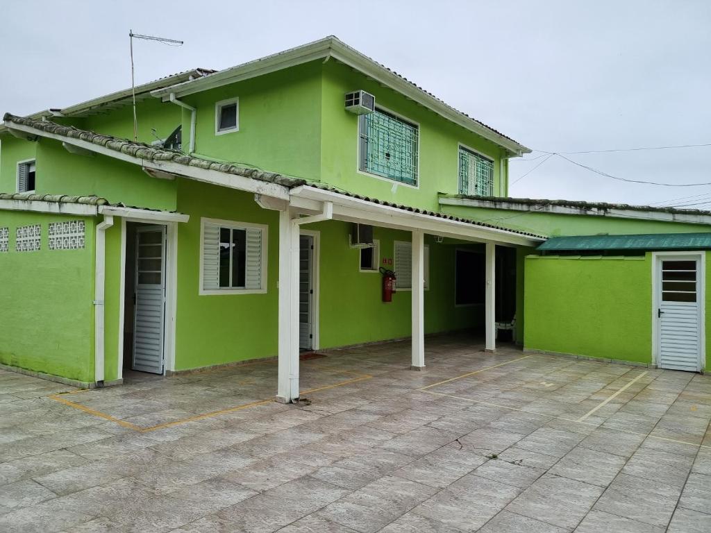 a green house with a parking lot in front of it at Kitnets em Caraguatatuba in Caraguatatuba