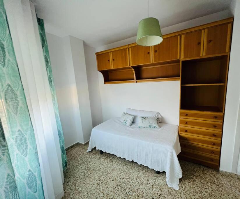 1 dormitorio con cama blanca y armarios de madera en Apartamento Almazara, en Valencia de Alcántara