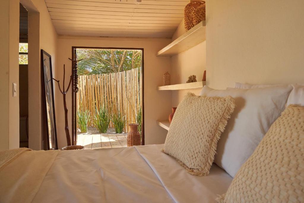 a bedroom with a bed with white sheets and a window at Evoé Caraíva in Caraíva