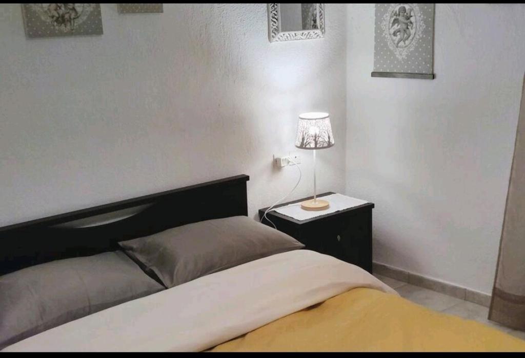 Evaggelia's Apartments 3 Διαμονή στο χωριό : غرفة نوم مع سرير ومصباح على كومودينو
