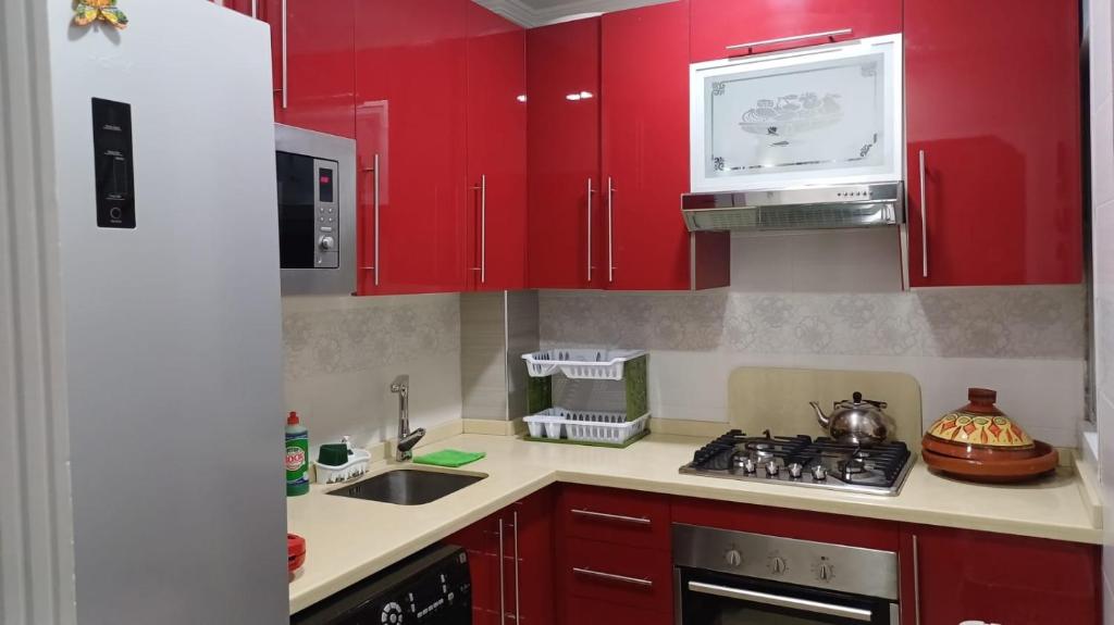 a kitchen with red cabinets and a stove top oven at soleil d'chamalo in Fnidek