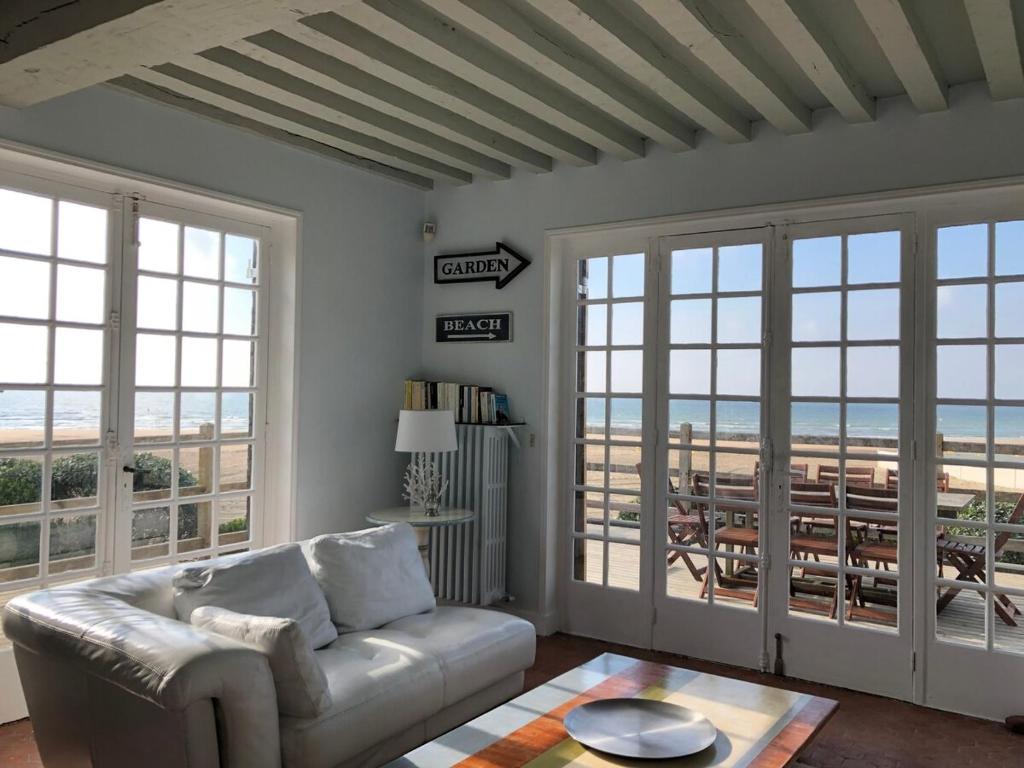 - un salon avec un canapé et une vue sur la plage dans l'établissement Face plage, vue mer, jardin - Deauville, à Benerville-sur-Mer