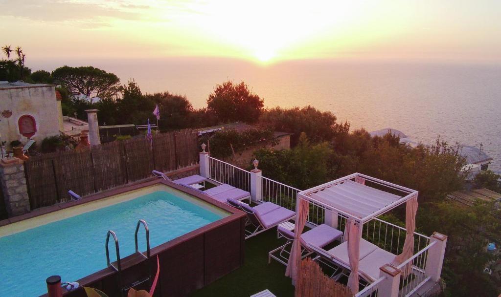 a swimming pool with chairs and the ocean at sunset at B&B Il Paradiso di Capri in Anacapri