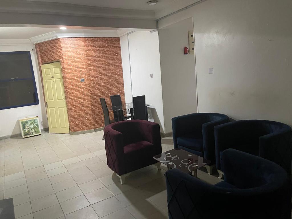 a waiting room with chairs and a table and a yellow door at Ibiyemi Apartment in Abuja