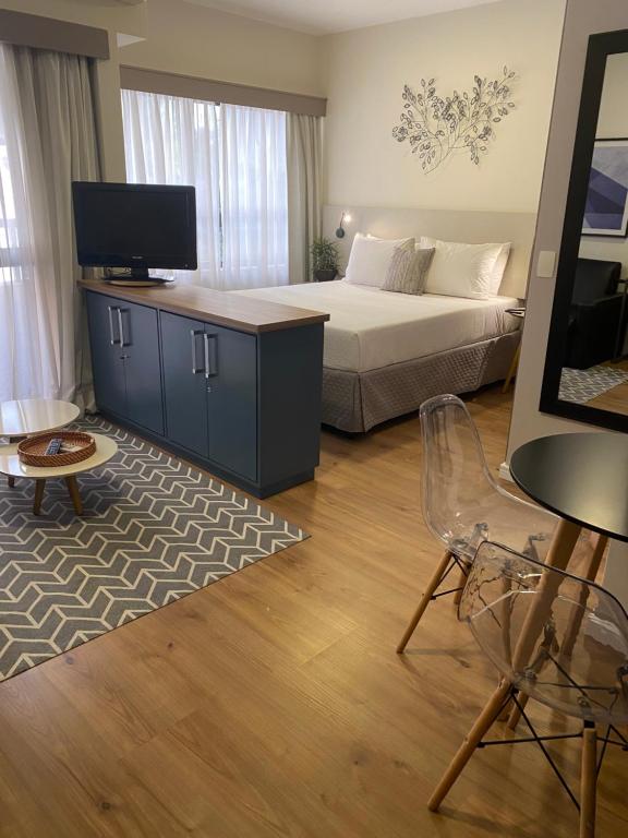 a bedroom with a bed and a tv and a chair at Flat Jardins, entre Av Paulista e Parque do Ibiraquera in São Paulo