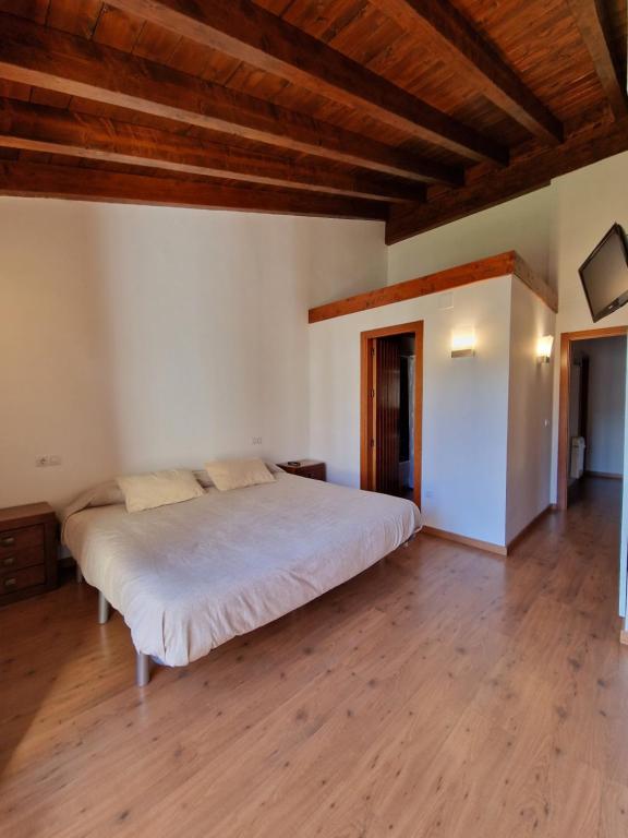 a bedroom with a large bed in a room with wooden ceilings at La casa del bosque in Alcalá de la Selva