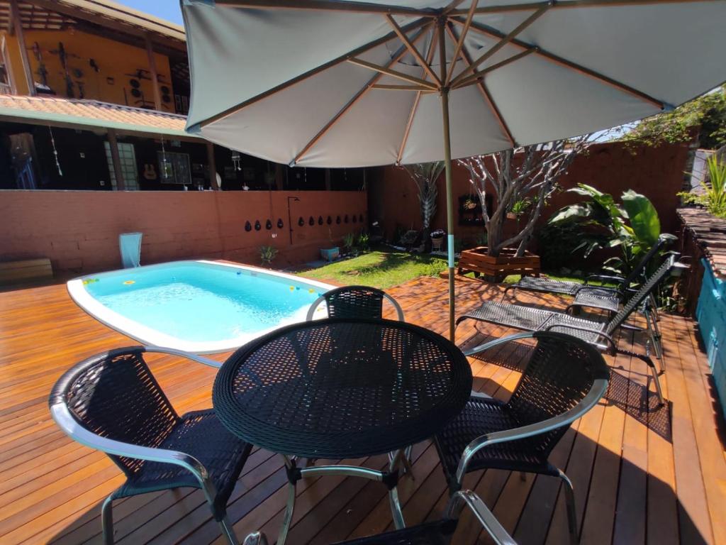 a table and chairs with an umbrella and a pool at Hostel Trem Di Durmi in Belo Horizonte