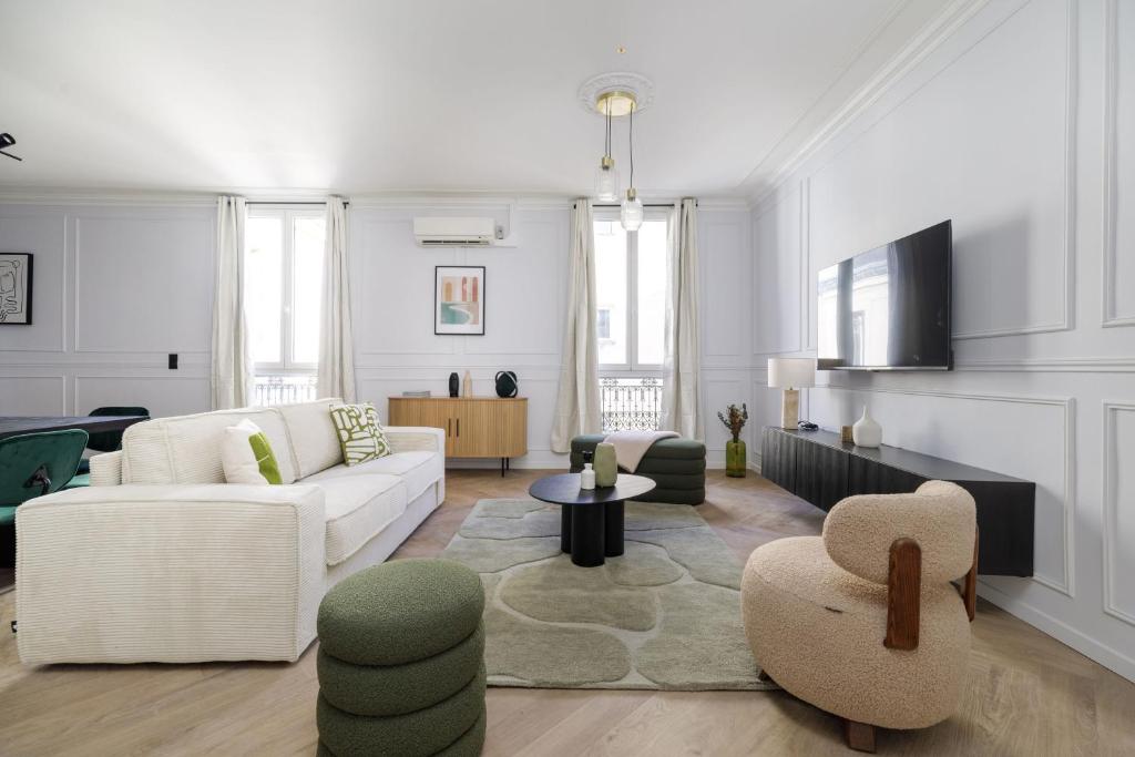 a living room with white furniture and a tv at Poetic Stay - Champs Elysees in Paris