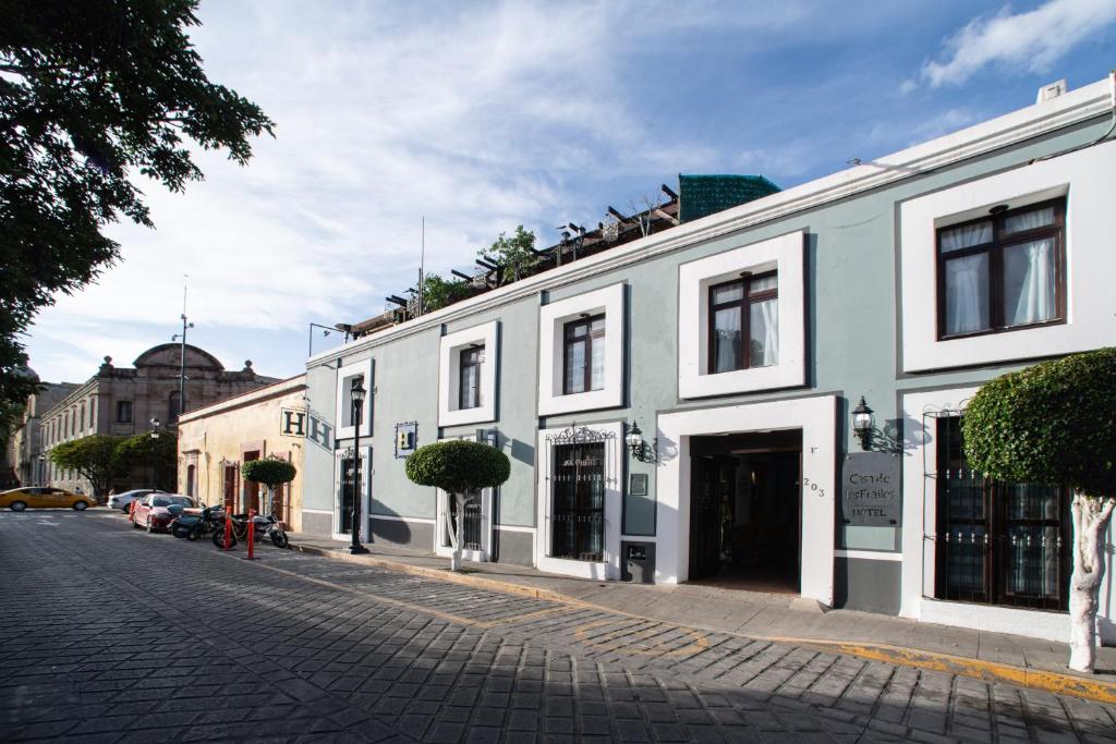 una calle adoquinada con un edificio blanco en Casa de los Frailes, en Oaxaca City