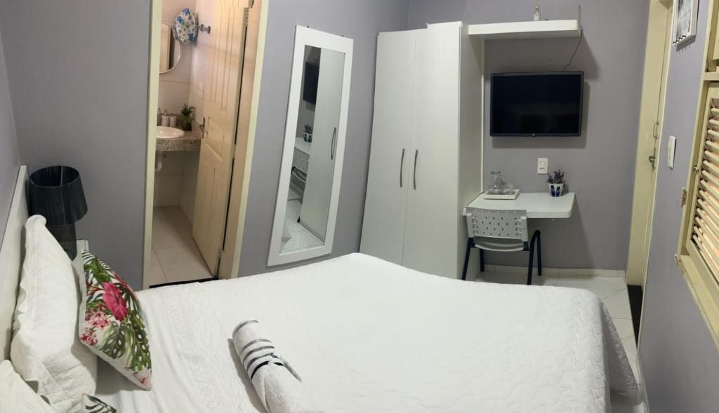 a small bedroom with a white bed and a desk at Executive207. Suíte completa com frigobar in Fortaleza