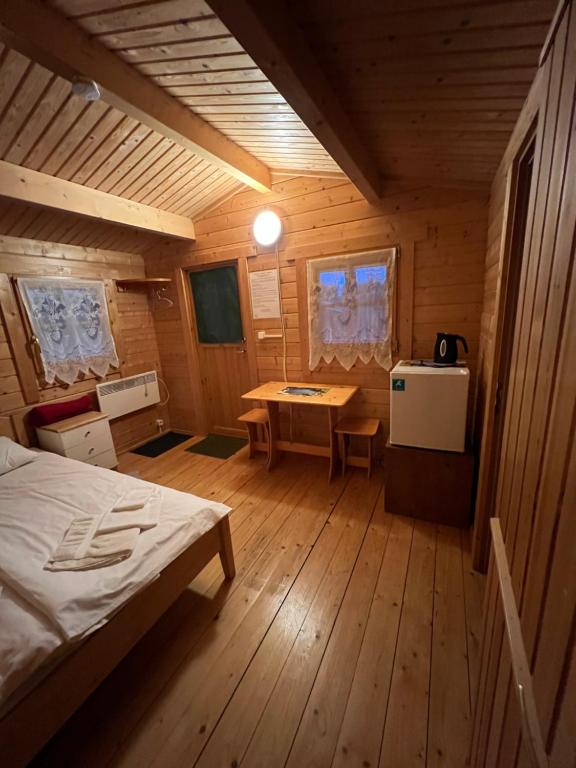 una habitación con una cama y una mesa en una cabaña en Artur´s Eaterie and Holiday home, en Viitna