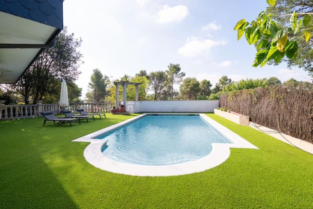 ein Pool in einem Garten mit grünem Gras in der Unterkunft Casa Farré next Barcelona Center in Pallejá