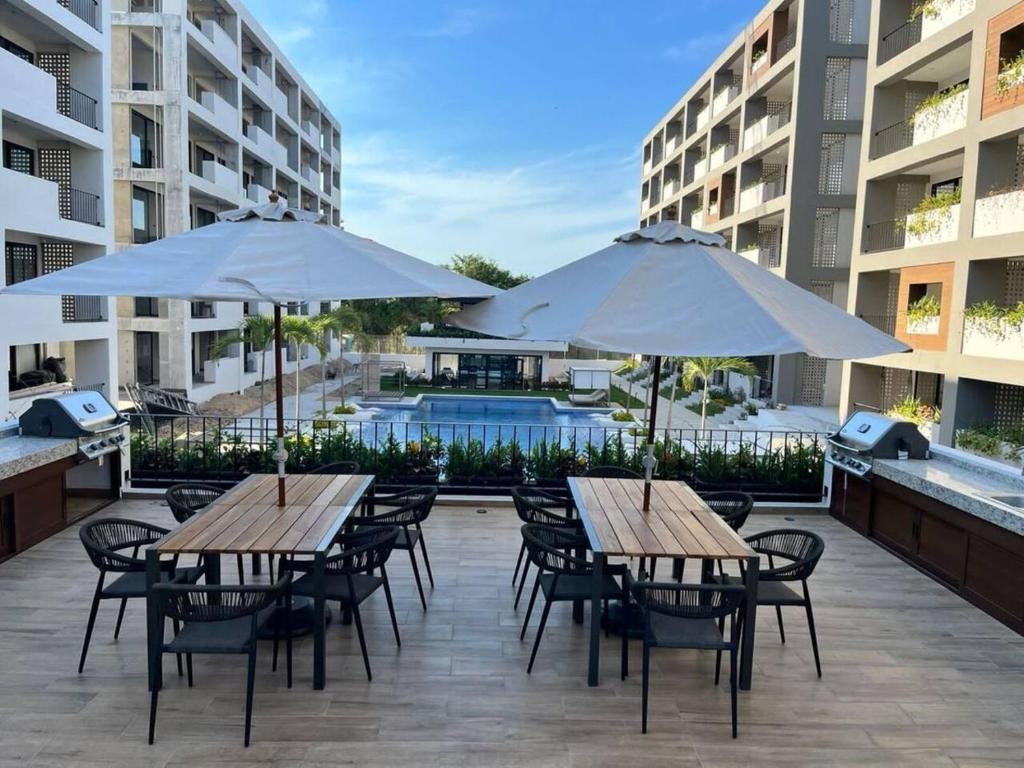 an outdoor patio with tables and chairs and umbrellas at Departamento nuevo con vista a la Piscina in Nuevo Vallarta 