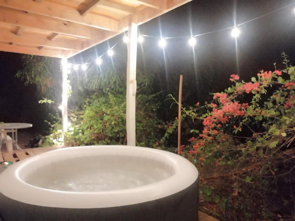 Cabaña en Pica con Jacuzzi privado في بيكا: حوض استحمام في غرفة بها زهور وأضواء