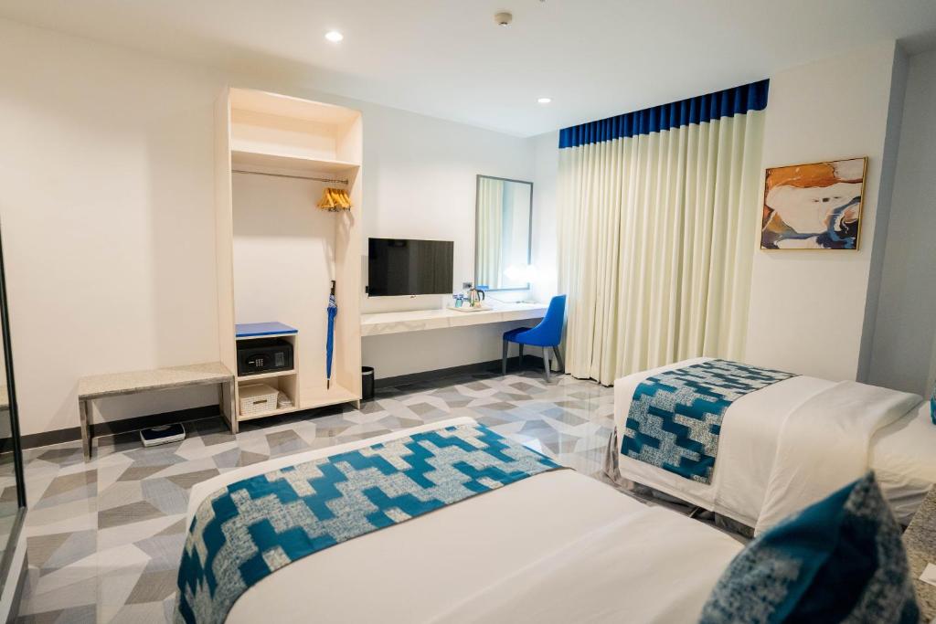 a hotel room with two beds and a television at Stacia Hotel powered by Cocotel in Cebu City