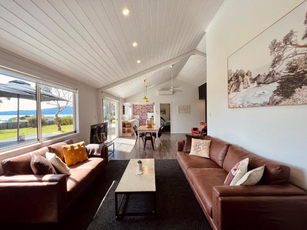 a living room with brown leather couches and a table at Boomers Retreat, Alonnah, Bruny Island in Alonnah