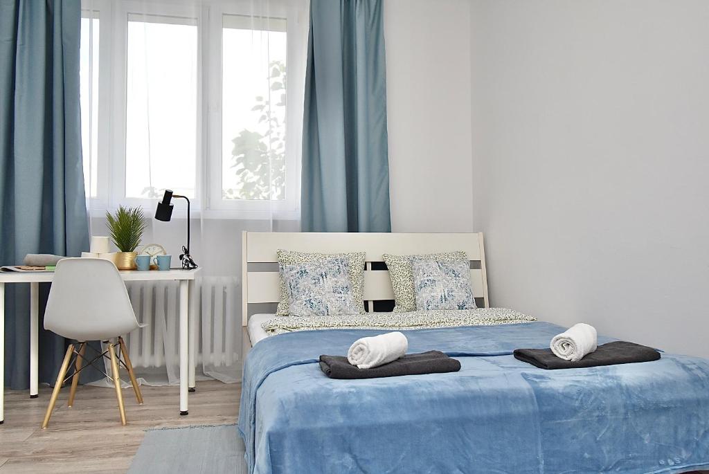 a bedroom with a blue and white bed with a desk at Rental Apartments Aleja Niepodległości in Warsaw