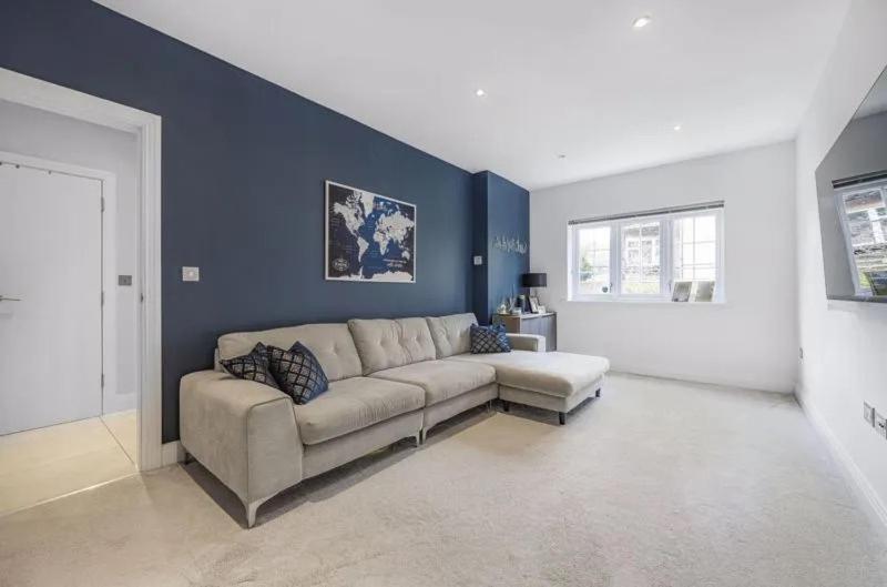 ein Wohnzimmer mit einem Sofa und einer blauen Wand in der Unterkunft Elegant 4-Bed Townhouse in Northampton - Free Parking in Northampton