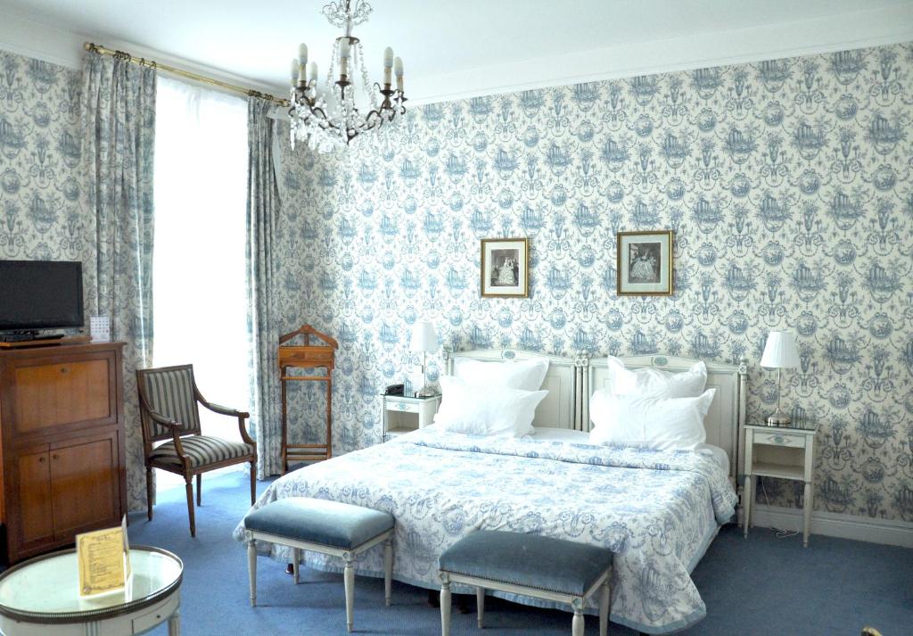 a bedroom with a bed and a chandelier at Grand Hôtel Des Templiers in Reims