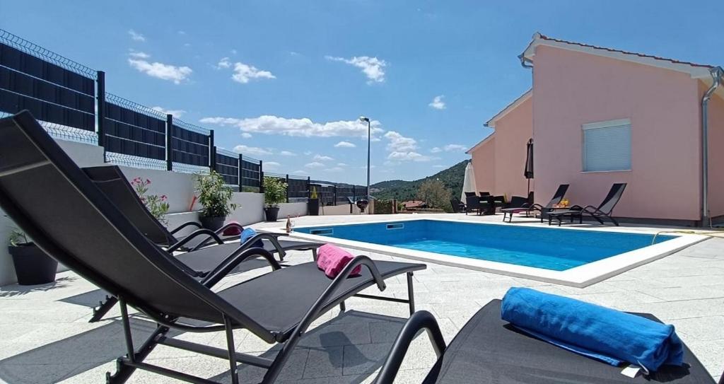 eine Gruppe von Stühlen neben einem Pool in der Unterkunft Family friendly house with a swimming pool Sibenik - 21939 in Šibenik