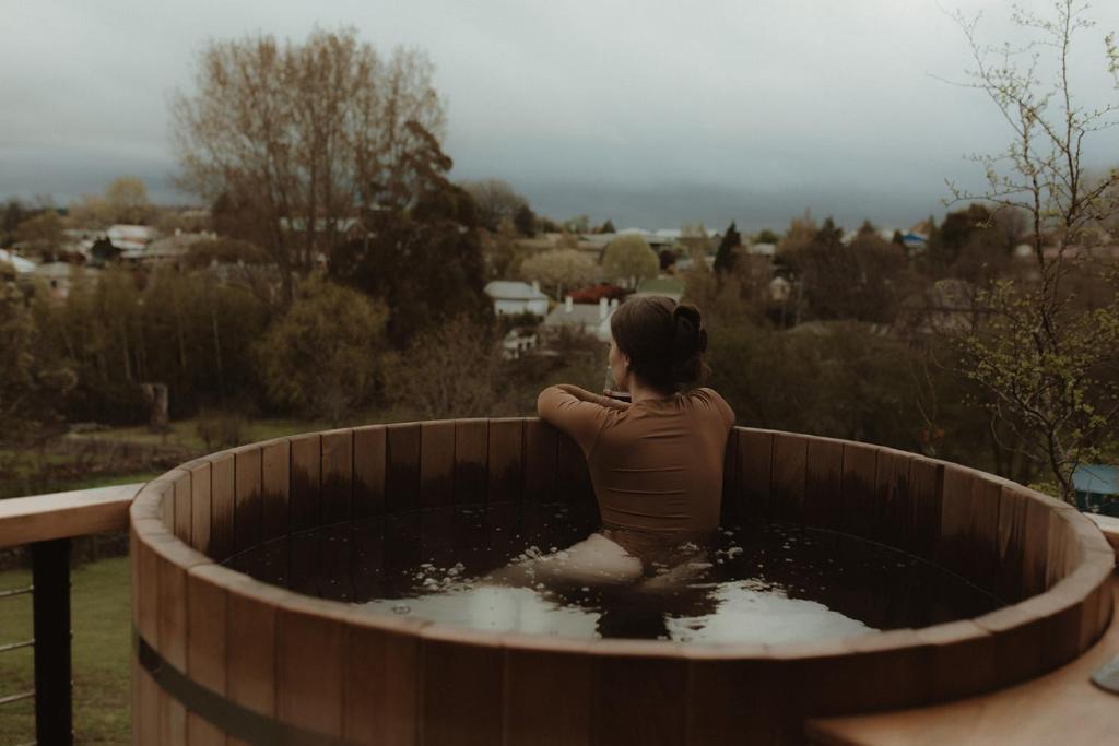 a woman sitting in a wooden tub filled with water at The Eco Cabin Tasmania in Deloraine