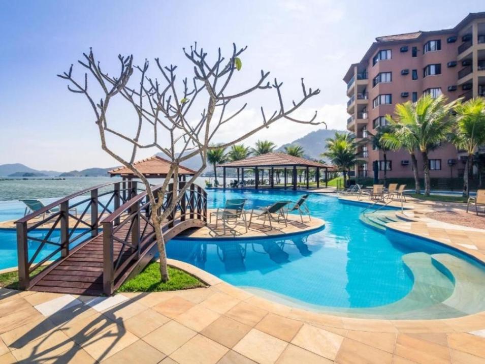 een groot zwembad met een brug en een resort bij Angra dos Reis - Apartamentos com Vista para o mar OU para piscina Condomínio Porto Bali in Angra dos Reis