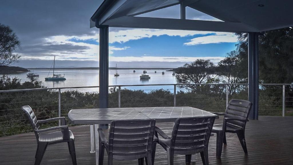 a table and chairs on a deck with a view of the water at Rest A Shore Coffin Bay in Coffin Bay
