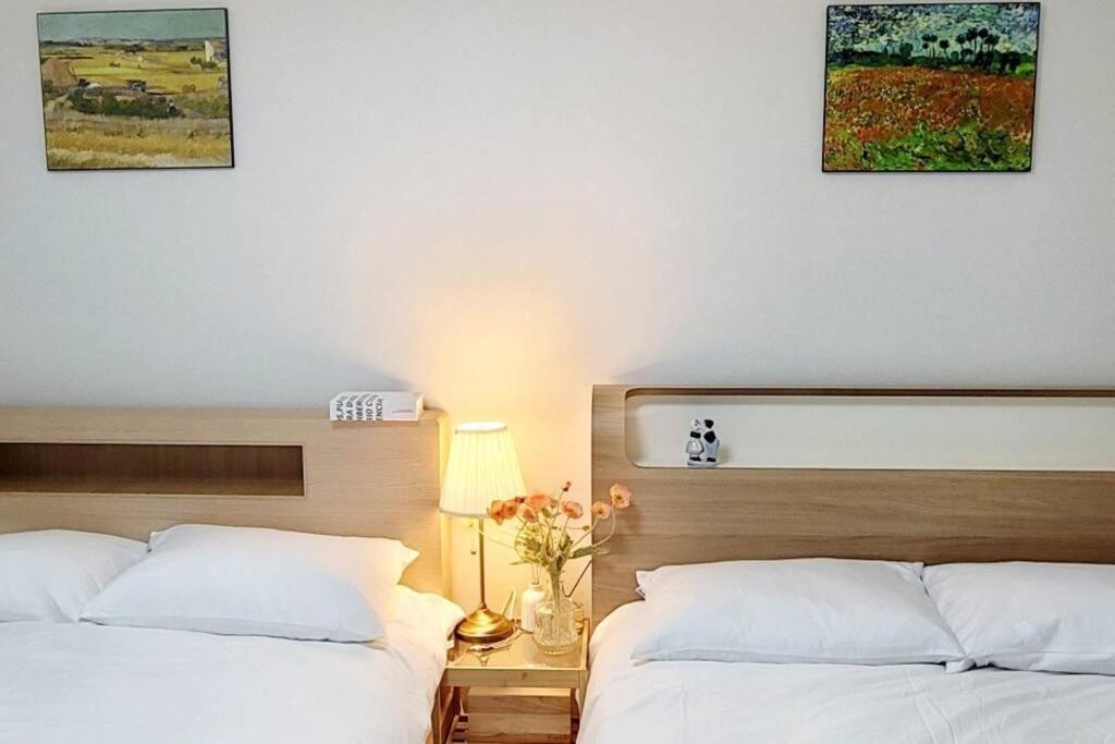 2 Betten in einem Schlafzimmer mit 2 Bildern an der Wand in der Unterkunft Stay Mono in Incheon