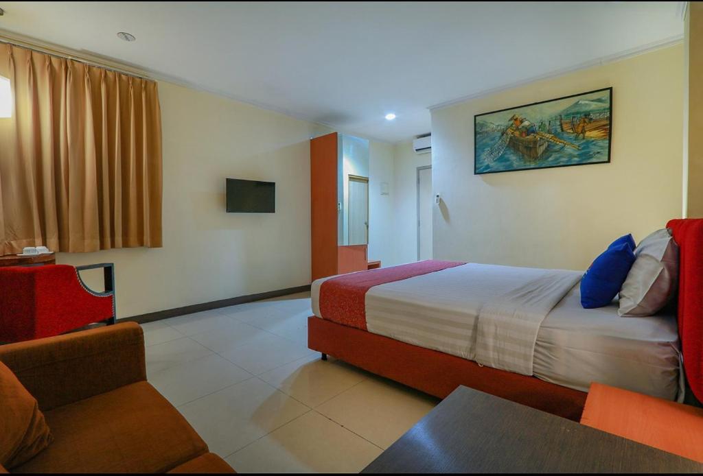 een hotelkamer met een bed en een bank bij Hotel Marlin Pekalongan in Pekalongan