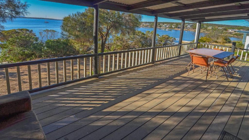 a deck with a table and chairs on the beach at CDC-625 Beach House in Coffin Bay