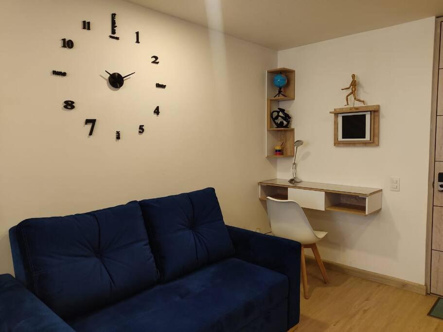 een woonkamer met een blauwe bank en een klok aan de muur bij Loft 2019 La Candelaria estrenar 24/7 in Bogota