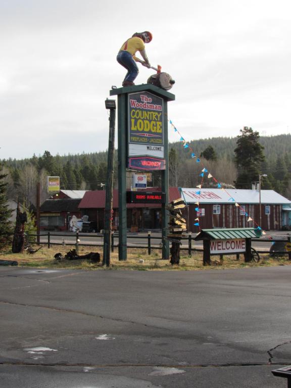 un hombre sentado encima de una señal en The Woodsman Country Lodge Motel, en Crescent