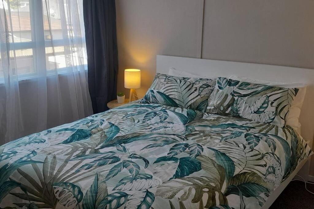a bedroom with a bed with a green and white comforter at City Central in Nelson