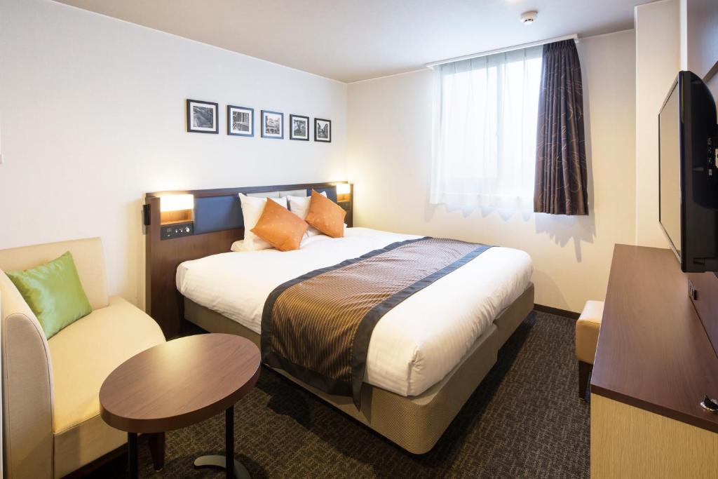 a hotel room with a bed and a couch at HOTEL MYSTAYS Kanazawa Castle in Kanazawa