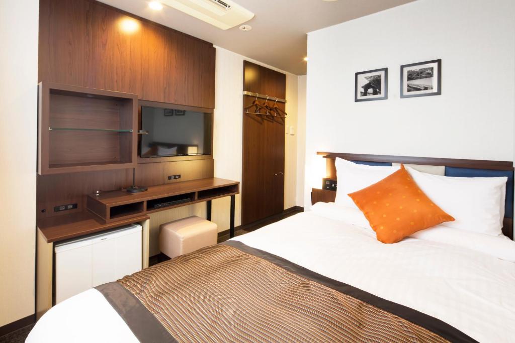 a bedroom with a bed and a desk with a television at HOTEL MYSTAYS Kanazawa Castle in Kanazawa
