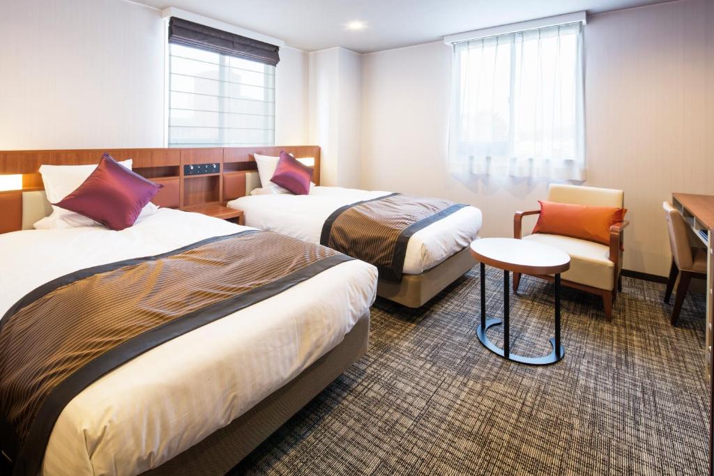 a hotel room with two beds and a chair at HOTEL MYSTAYS Kanazawa Castle in Kanazawa