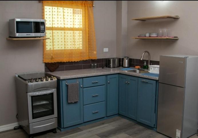 uma cozinha com armários azuis e um micro-ondas em Comfi Spaces em Canaan