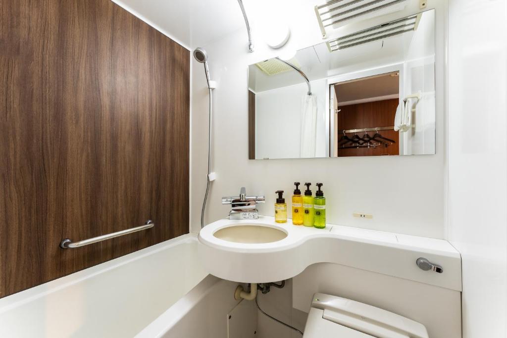 a bathroom with a sink and a toilet and a mirror at HOTEL MYSTAYS Kanazawa Castle in Kanazawa