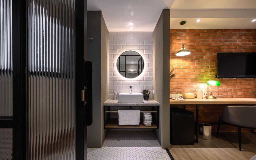 a bathroom with a sink and a desk with a mirror at Hotel East Taichung in Taichung