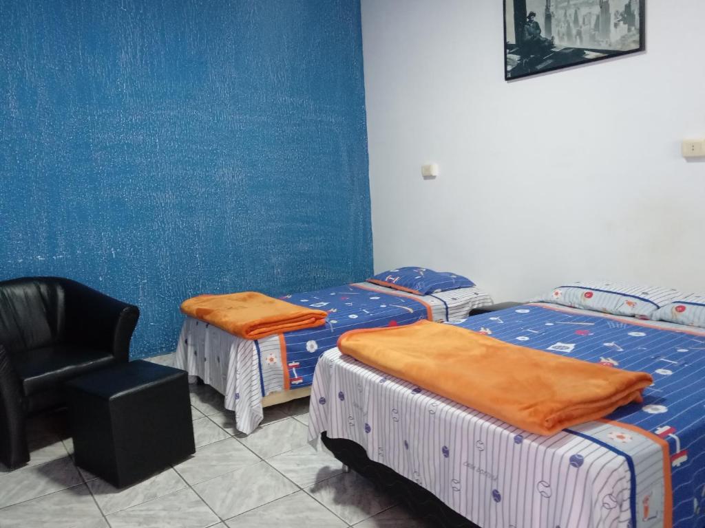 een kamer met drie bedden en een stoel erin bij El Viajero Hostel & Suítes 10 in Pedro Juan Caballero