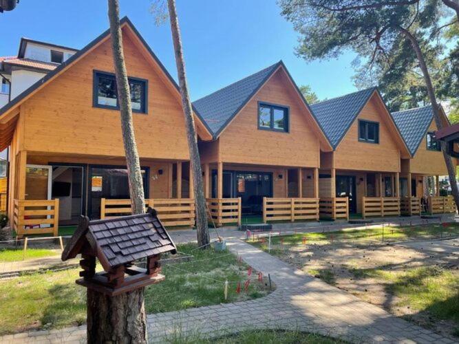 una grande casa in legno con una panchina di fronte di Comfortable holiday homes for 6 people, close to the sea a Dziwnówek