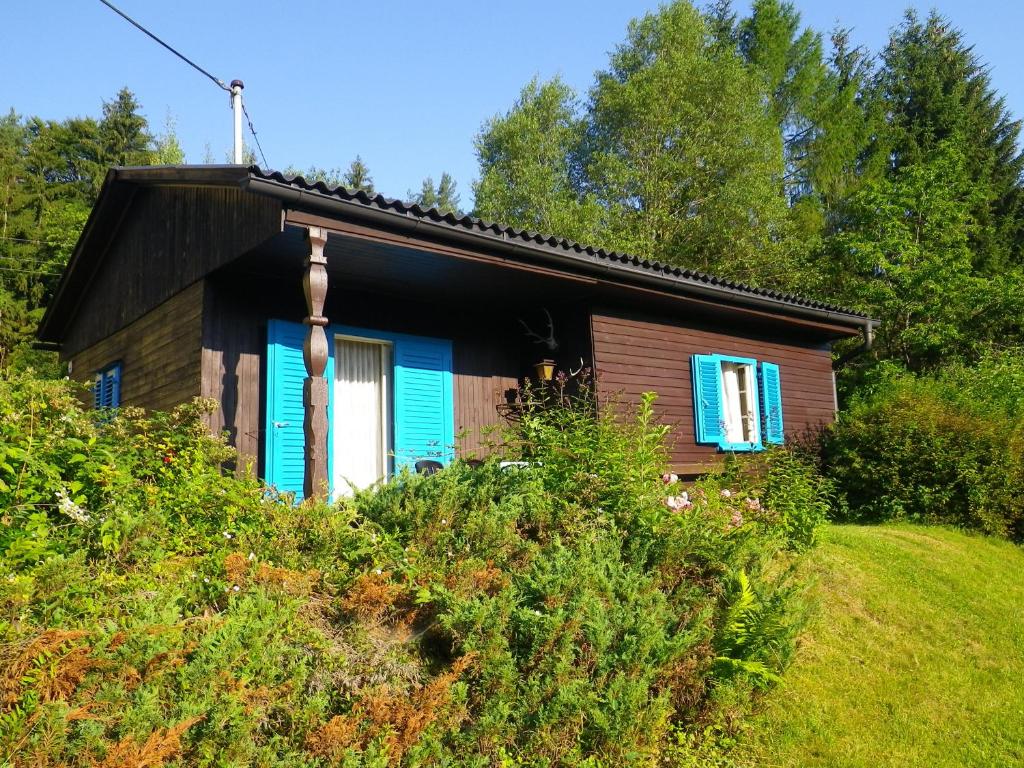 a small house with a blue window on a hill at Ferienhaus Abhau-Tage in Ferlach