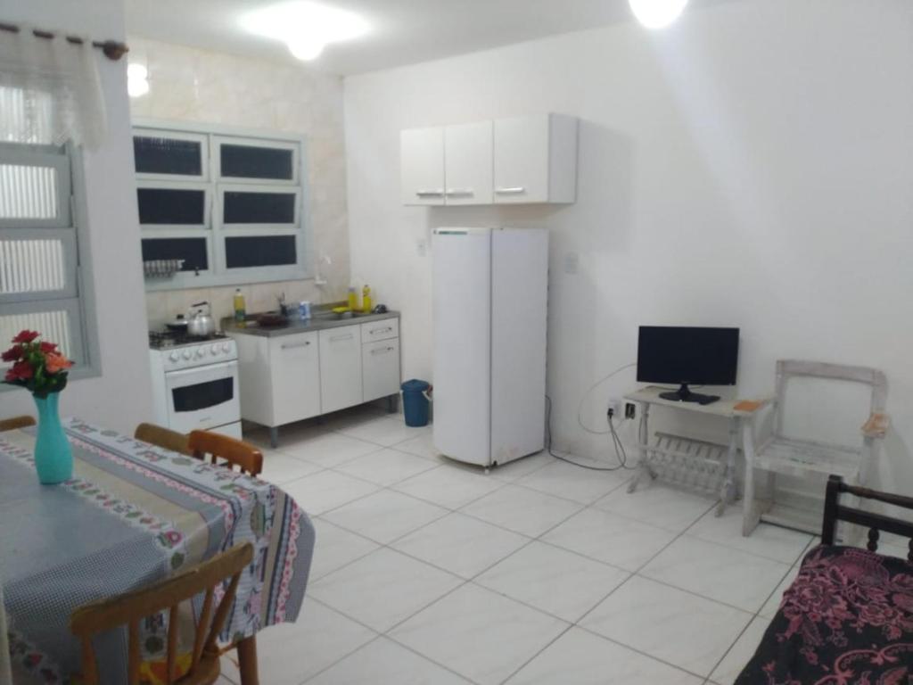 a white kitchen with a table and a refrigerator at AP beira mar perto do centro in Capão da Canoa